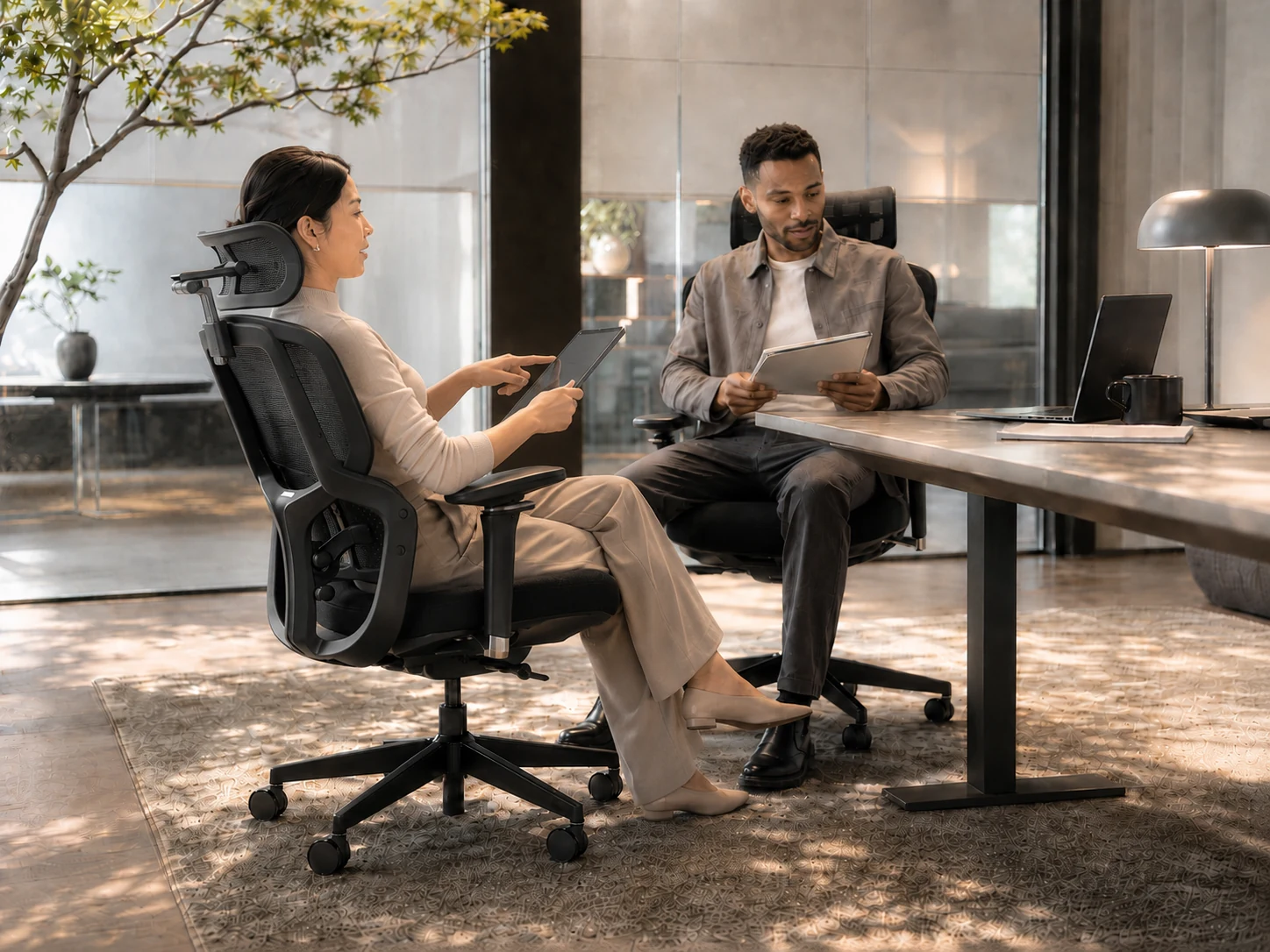 Two professionals seated in DRAKARA ergonomic chairs in a contemporary office